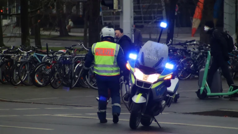 Intervention de police avec gyrophares bleus allumés dans une rue avec une trottinette électrique visible en arrière-plan.