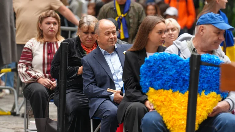 Des habitants de Ķekava réunis lors d'une cérémonie d'hommage avec des symboles ukrainiens.