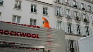 Des panneaux d'isolation Rockwool empilés sur un chantier de rénovation devant des immeubles résidentiels.