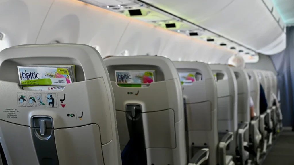 airBaltic lidmašīnas sēdekļu rindas ar aviokompānijas zīmola žurnāliem, gatavojoties jaunam lidojumam no Viļņas.