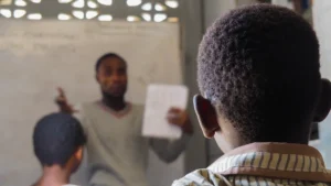 Skolotājs klasē skaidro mācību vielu, akcentējot pedagoga lomu jauno speciālistu atbalsta programmā.