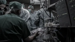 Ārstu komanda veic sarežģītu operāciju modernā operāciju zālē ar medicīnas ierīcēm un monitoriem.
