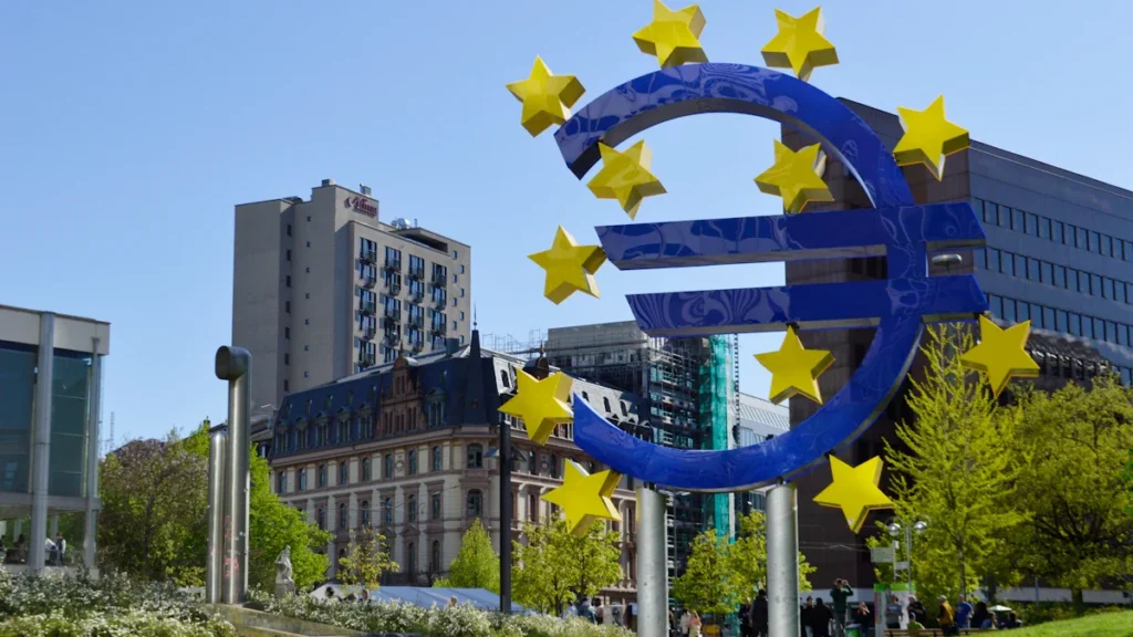 Eiropas Centrālās bankas simbols Frankfurtē ar zvaigznēm un zilu eiro zīmi.