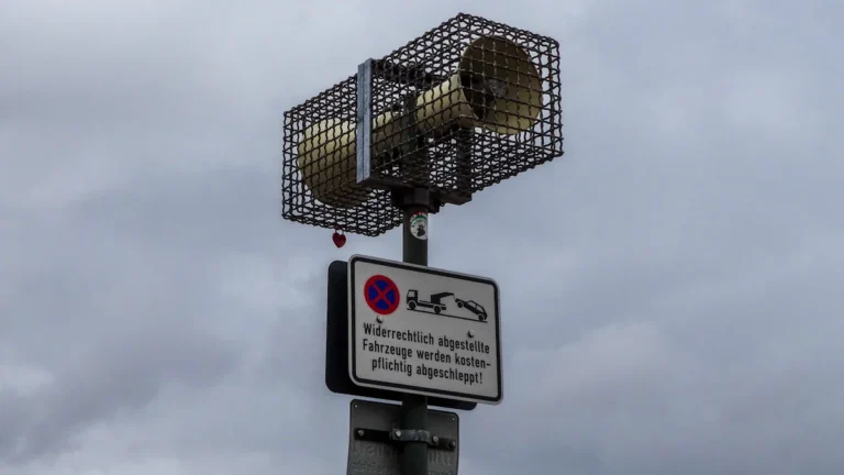Āra trauksmes sirēna, kas piestiprināta pie staba uz pelēku debesu fona.