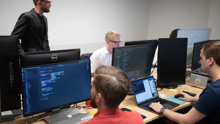 Cilvēki pie datoru ekrāniem apgūst modernas digitālās prasmes un programmēšanu.