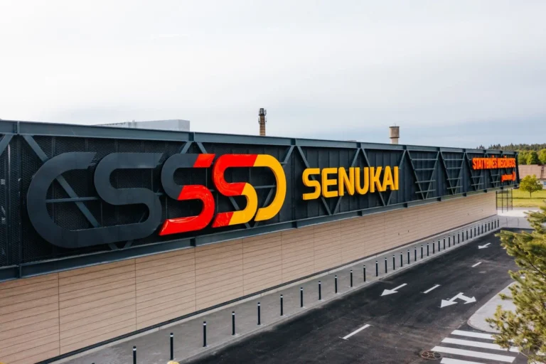 Senukai veikala ēka ar lielu SSS logotipu un asfalta ceļu ar baltām bultiņām.