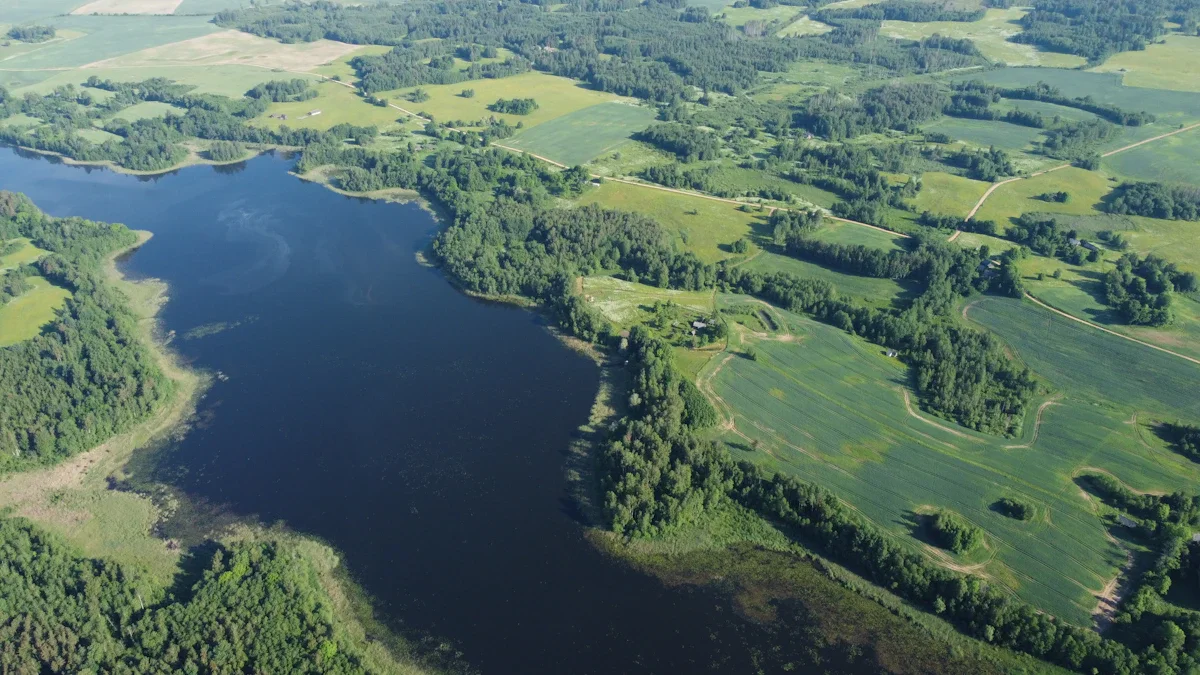 Aerofotoattēls ar Latvijas ainavu, kurā redzams liels ezers un apkārtējie zaļie lauki.