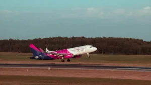 Wizz Air pasažieru lidmašīna paceļas no Viļņas lidostas skrejceļa uz skaidru debesu fona.