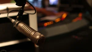 Profesionāls mikrofons ierakstu studijā uz pults fona, ilustrējot radio romāna ieraksta procesu.