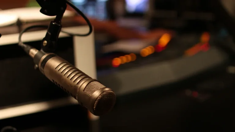 Profesionāls mikrofons ierakstu studijā uz pults fona, ilustrējot radio romāna ieraksta procesu.
