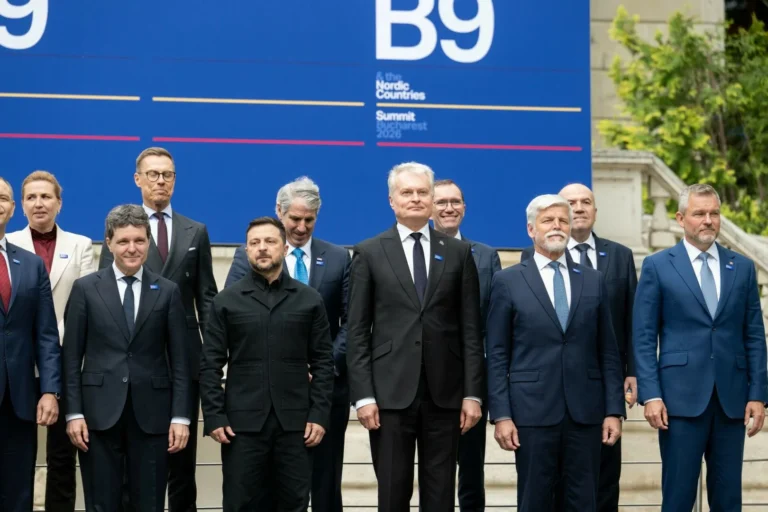 Valstu vadītāji, tostarp Zelenskis un Nausēda, stāv kopīgā fotogrāfijā pie zila samita reklāmkaroga.
