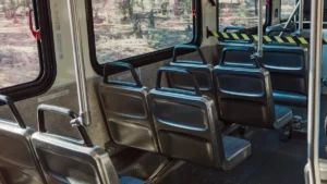 Sabiedriskā transporta autobusa salons ar pelēkiem sēdekļiem, simbolizējot pilsētas plānotās izmaiņas pakalpojumu pieejamībā.