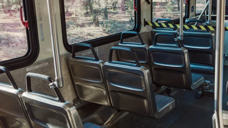 Sabiedriskā transporta autobusa salons ar pelēkiem sēdekļiem, simbolizējot pilsētas plānotās izmaiņas pakalpojumu pieejamībā.