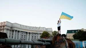 Zēns ar Ukrainas karogu stāv uz iznīcināta krievu tanka Kijivā