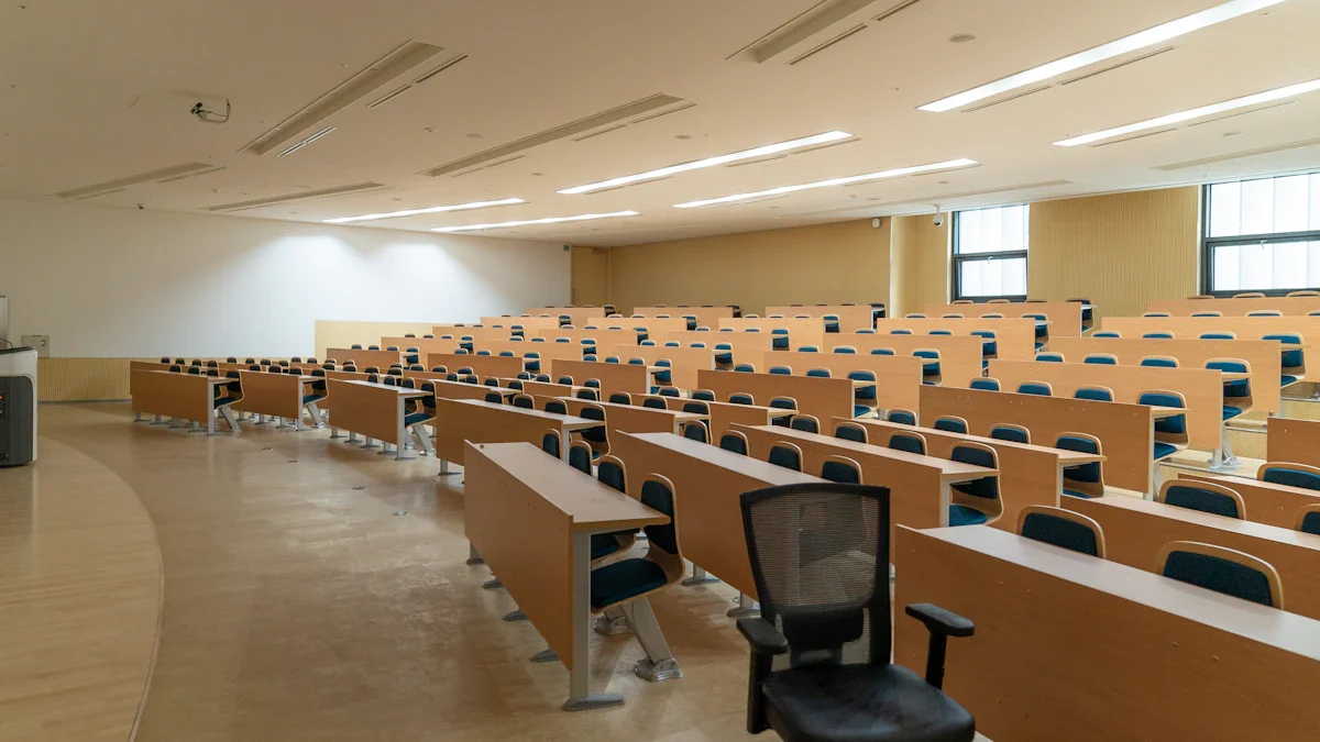 Tukša moderna universitātes lekciju zāle ar gaišiem koka galdiem un melnu krēslu priekšplānā.