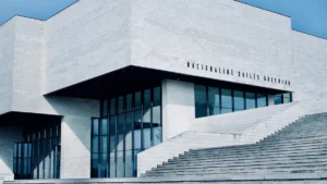 Mūsdienīga balta betona ēka Viļņā zem skaidrām zilām debesīm, simbolizējot pilsētas tehnoloģisko izaugsmi.