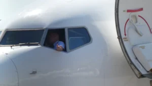 Lidmašīnas pilots raugās pa kokpita logu, gatavojoties lidojumam virs Eiropas pilsētām.