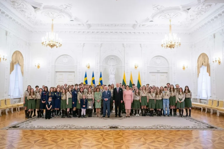 Zviedrijas karalis, karaliene un Lietuvas prezidenta pāris pozē kopā ar skautu grupu greznā baltā zālē.