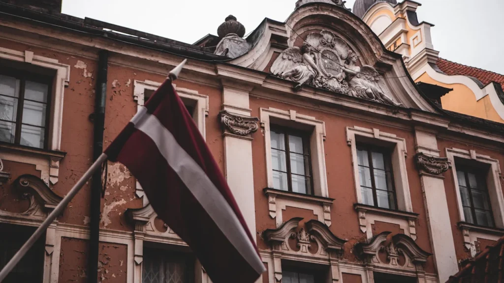 Latvijas karogs plīvo pie vēsturiskas ēkas fasādes Rīgā, Latvijā.