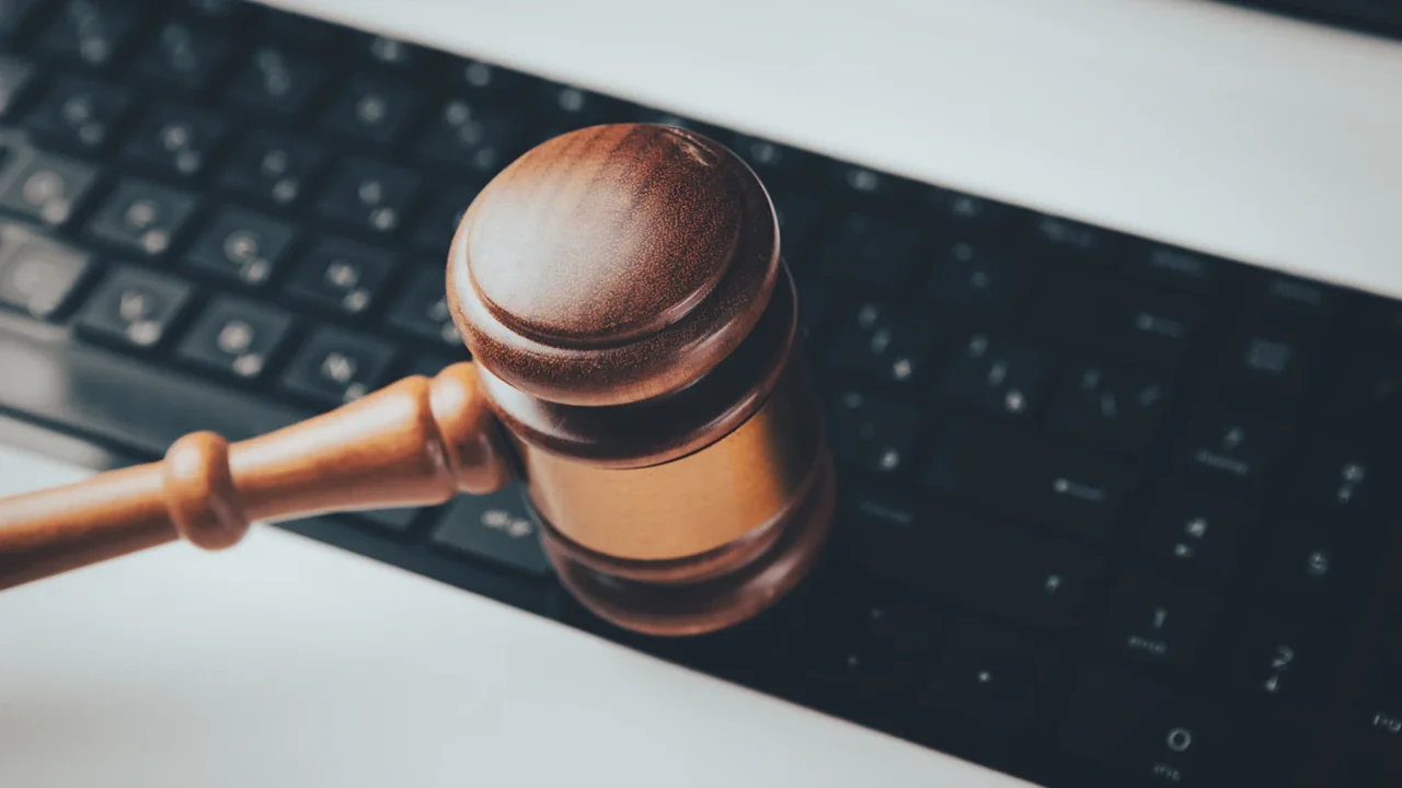 Tiesneša āmuriņš uz datora tastatūras, simbolizējot mākslīgā intelekta regulējumu un likumdošanu.