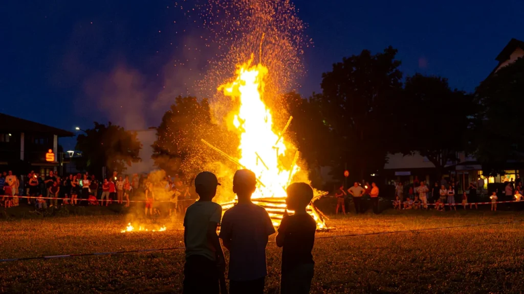 Bērni vēro lielu, tradicionālu Jāņu ugunskuru naksnīgās debess fona krēslas stundā.