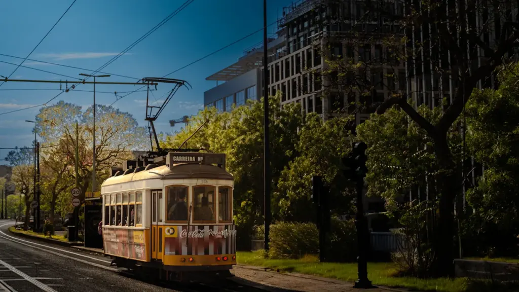 Dzeltens retro stila tramvajs brauc pa pilsētas ielu saulainā dienā.