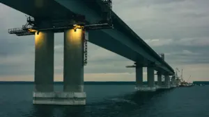Liels tilts pār plašu ūdenstilpi, kas simbolizē pilsētas infrastruktūras attīstību un transporta nozīmi.