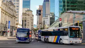 Pilsētas autobuss brauc pa ielu gaišā dienas laikā pilsētas centrā.