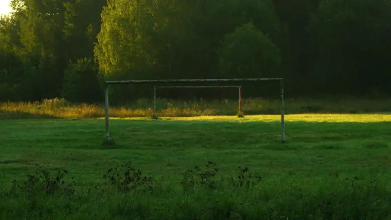 Tukši futbola vārti zālienā rīta gaismā Laucienes sporta bāzes pasākuma tematikai.