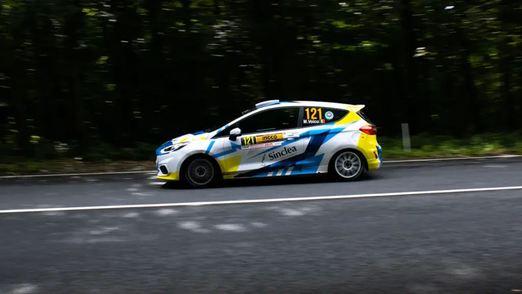 Sporta rallija automašīna ātri brauc pa lauku ceļu Ogres novada vasaras piedzīvojumā.