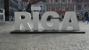 Liels uzraksts RĪGA uz bruģētas ielas vēsturiskajā Rīgas pilsētas centrā.